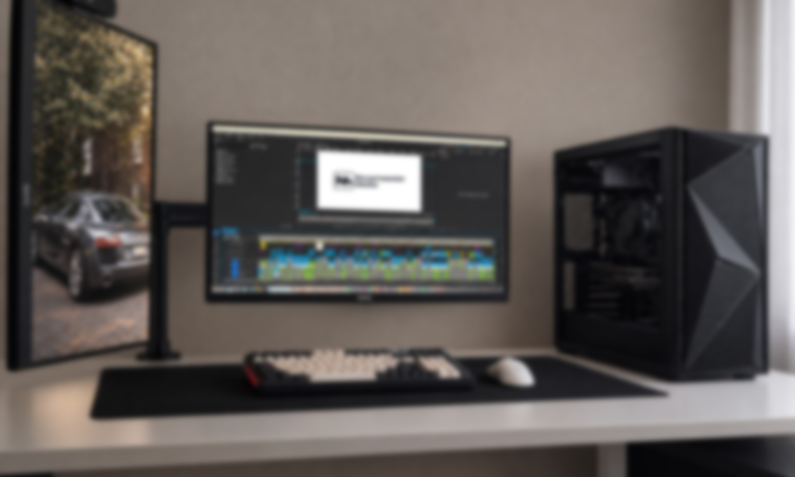 Werkplek met drie schermen waarop video wordt gemonteerd